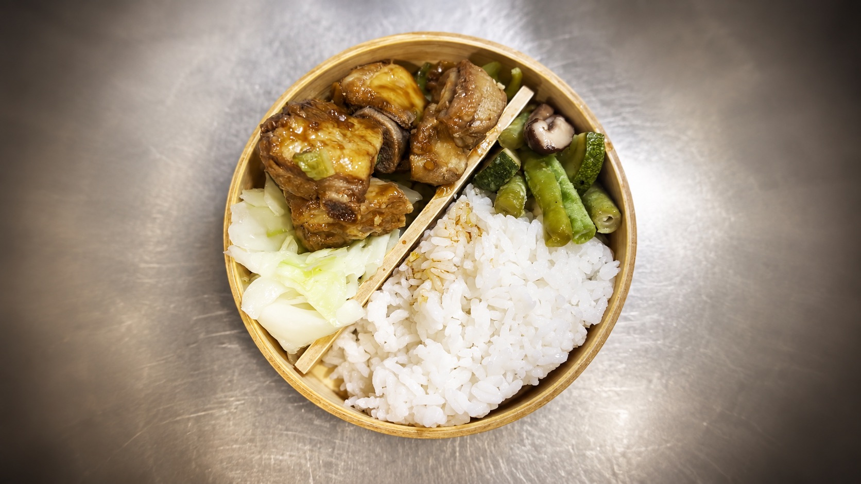 金色便當盒裡盛著蒜香醬燒排骨、白飯與蔬菜